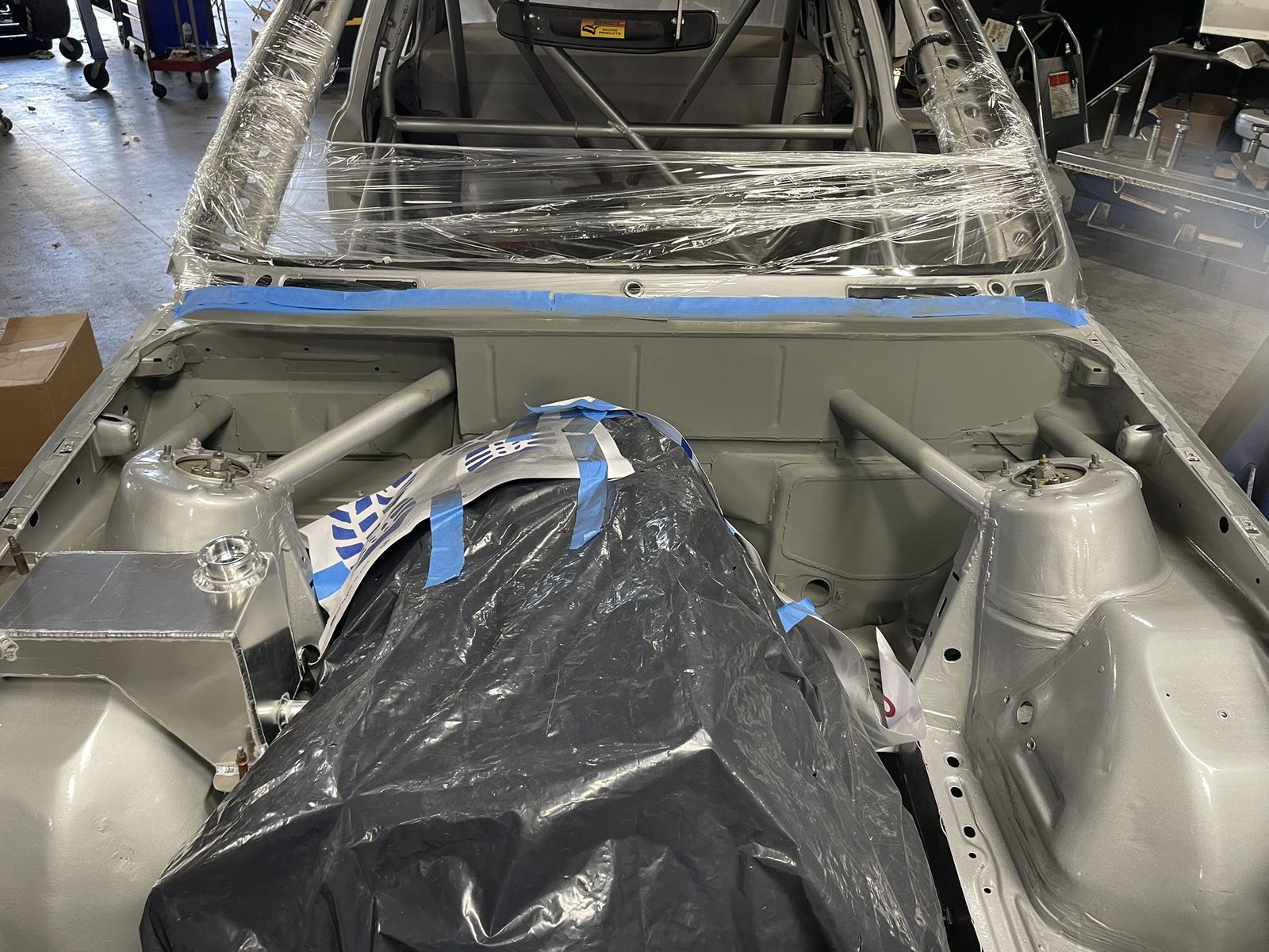 Stripped BMW Z3 track car interior with roll cage, fuel cell and coilover top mounts